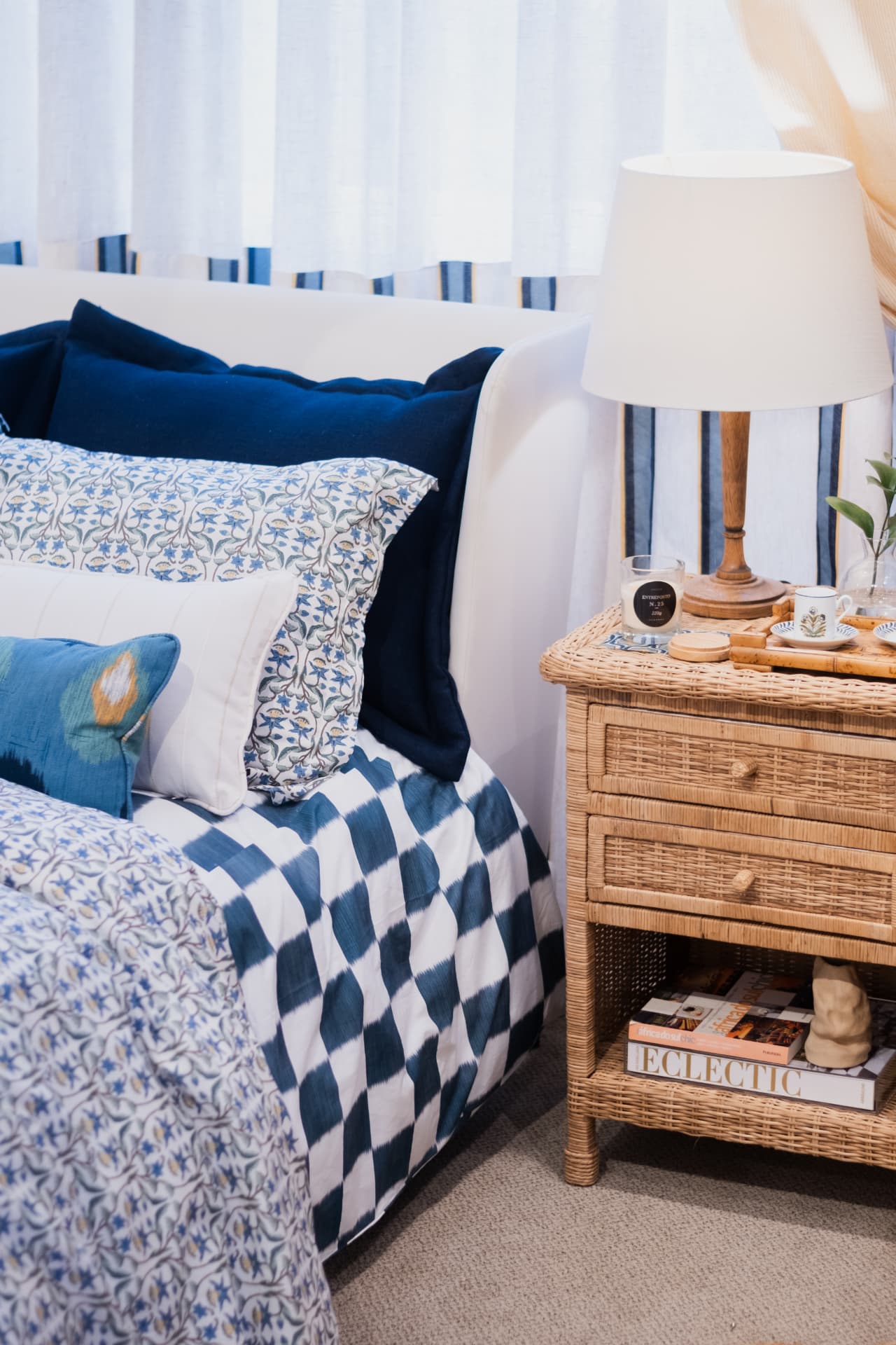 Quarto em azul e branco com roupa de cama estampada e criado-mudo de vime · Luize Home